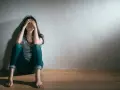 En kvinna sitter på golvet med händerna över ansiktet, en bild som symboliserar grov depression och ensamhet.