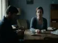 En kvinna och en man sitter vid ett bord med kaffe. Mannen tittar ner, kvinnan ser orolig ut. En känsla av triangulering och narcissism hänger i luften.