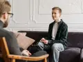 En ung man har ett kbt samtal med en terapeut i ett ljust rum.