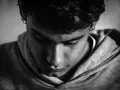 En ung person med örhängen i en hoodie, blicken nedåt. Kanske ett uttryck för dystymi symtom.