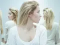 En kvinna med blont hår tittar åt sidan, omgiven av spegelbilder. En visuell representation av en kvinnlig psykopat checklista.
