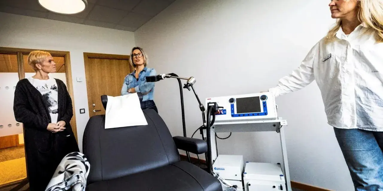 Kvinnor vid utrustning för magnetbehandling depression. En stol och medicinsk apparatur står redo.