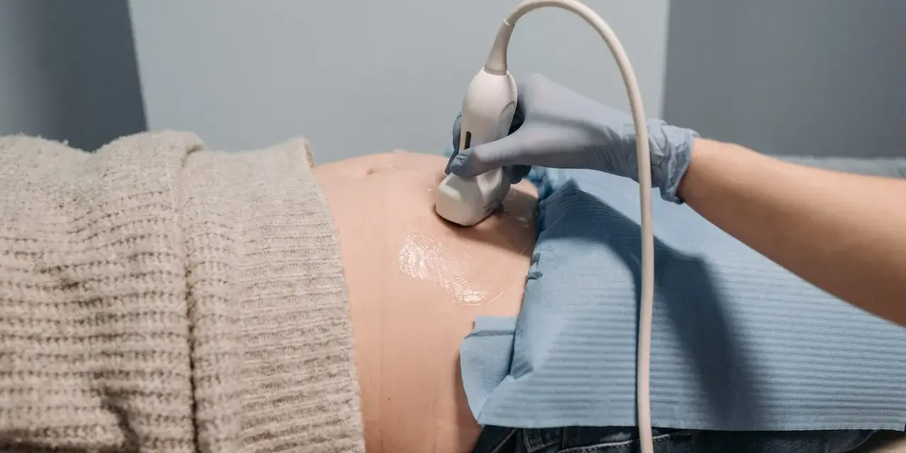 En hand i blå handske utför ultraljud på en gravid mage. En ny fas i livet, inte en gravid depression test.