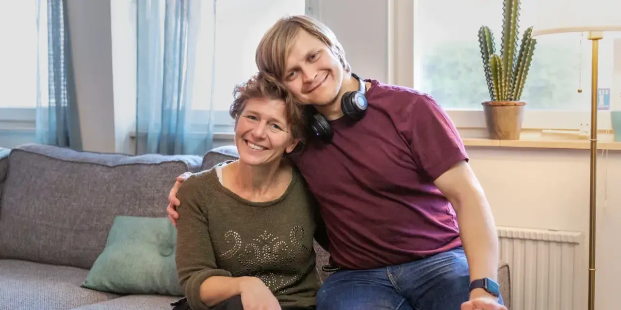 En ung man vilar sitt huvud på en kvinnas axel. De ler mot kameran, en bild som får en att **visa medlidande** för deras starka band.