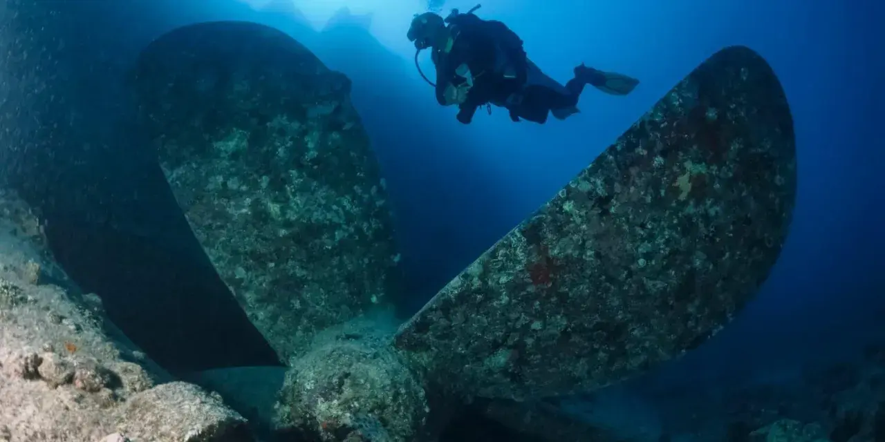 Dykare nära ett enormt skeppspropeller. Ett klaustrofobi test för den som inte gillar trånga utrymmen under vattnet.