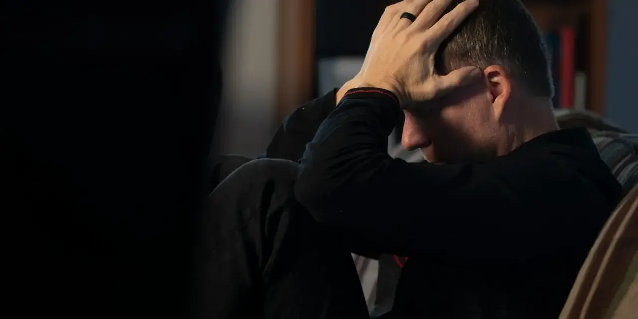 Man med händerna mot huvudet, djupt försjunken i tankar. En påminnelse om att bli mentalt stark genom svåra stunder.