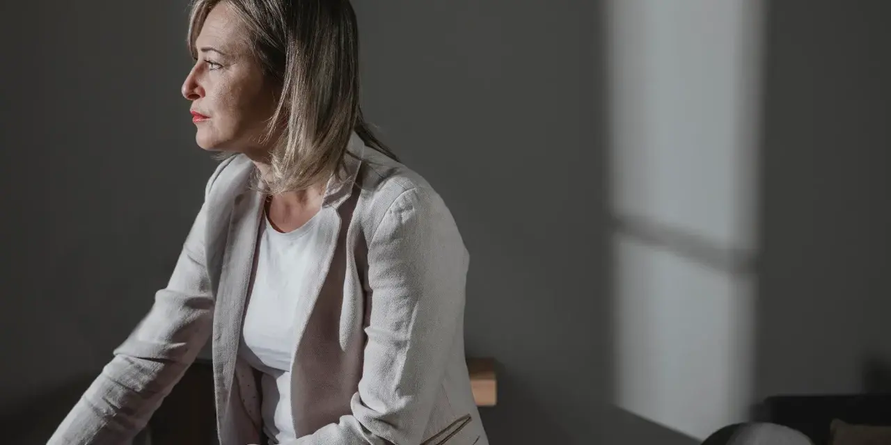 En kvinna i profil, med tankarna på att byta jobb efter utmattning. Ljuset faller mjukt över hennes ansikte.