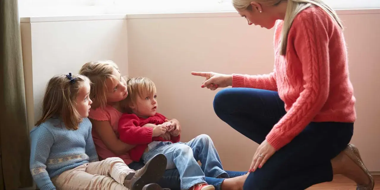 Kvinna pekar på barn som sitter på golvet. En svår samarbetssamtal med narcissist.