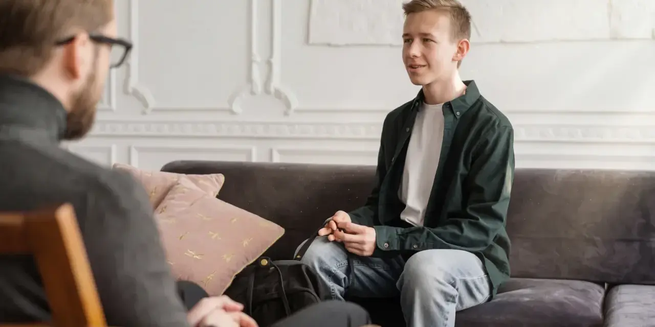 En ung man sitter i samtal med en terapeut. En viktig del av psykoterapi behandling är att skapa en trygg miljö.