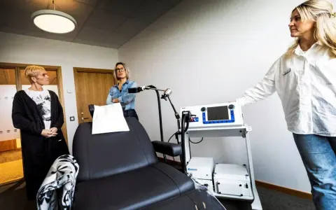 Kvinnor vid utrustning för magnetbehandling depression. En stol och medicinsk apparatur står redo.