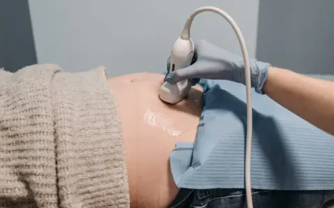 En hand i blå handske utför ultraljud på en gravid mage. En ny fas i livet, inte en gravid depression test.