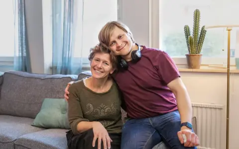 En ung man vilar sitt huvud på en kvinnas axel. De ler mot kameran, en bild som får en att **visa medlidande** för deras starka band.