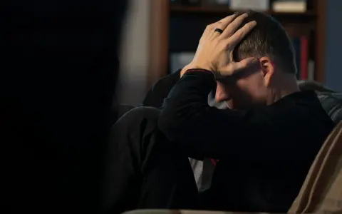 Man med händerna mot huvudet, djupt försjunken i tankar. En påminnelse om att bli mentalt stark genom svåra stunder.