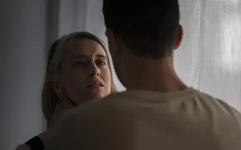En kvinna med en blick som vittnar om inre styrka möter en mans blick.