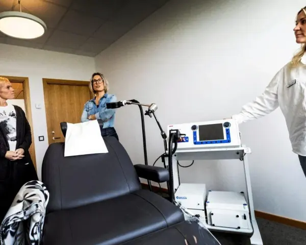 Kvinnor vid utrustning för magnetbehandling depression. En stol och medicinsk apparatur står redo.