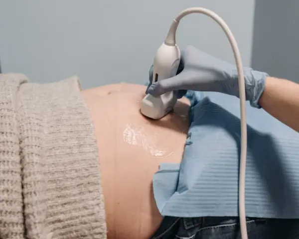 En hand i blå handske utför ultraljud på en gravid mage. En ny fas i livet, inte en gravid depression test.