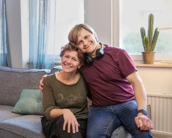 En ung man vilar sitt huvud på en kvinnas axel. De ler mot kameran, en bild som får en att **visa medlidande** för deras starka band.