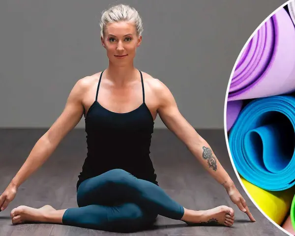 Kvinna i yogaposition, redo för liggande meditation. Rullade yogamattor i bakgrunden.