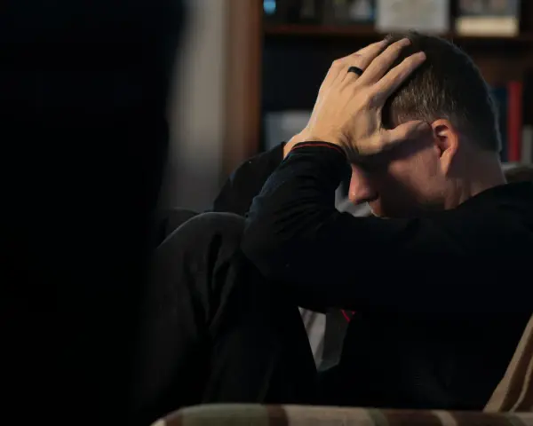 Man med händerna mot huvudet, djupt försjunken i tankar. En påminnelse om att bli mentalt stark genom svåra stunder.