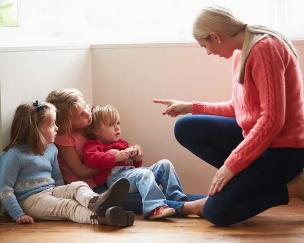Kvinna pekar på barn som sitter på golvet. En svår samarbetssamtal med narcissist.