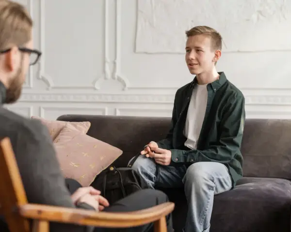 En ung man sitter i samtal med en terapeut. En viktig del av psykoterapi behandling är att skapa en trygg miljö.