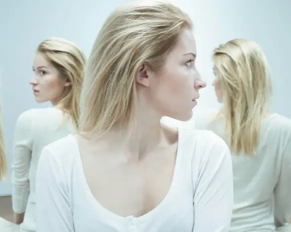 En kvinna med blont hår tittar åt sidan, omgiven av spegelbilder. En visuell representation av en kvinnlig psykopat checklista.