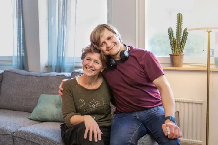 En ung man vilar sitt huvud på en kvinnas axel. De ler mot kameran, en bild som får en att **visa medlidande** för deras starka band.