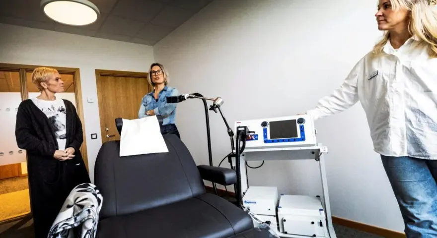 Kvinnor vid utrustning för magnetbehandling depression. En stol och medicinsk apparatur står redo.