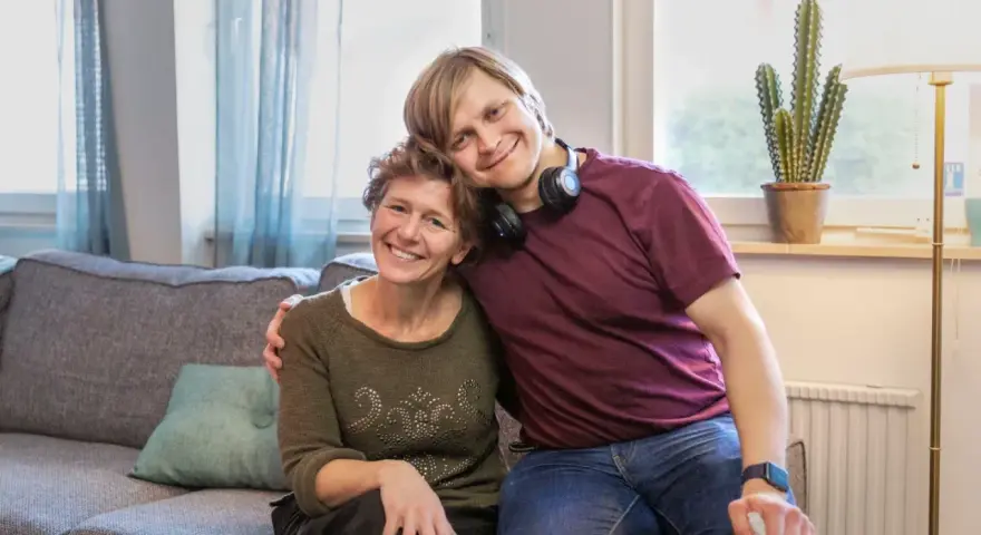 En ung man vilar sitt huvud på en kvinnas axel. De ler mot kameran, en bild som får en att **visa medlidande** för deras starka band.