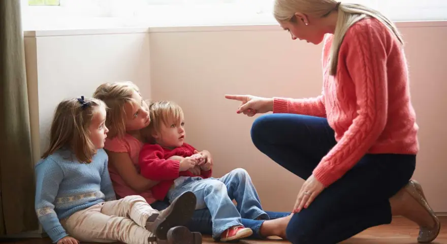 Kvinna pekar på barn som sitter på golvet. En svår samarbetssamtal med narcissist.
