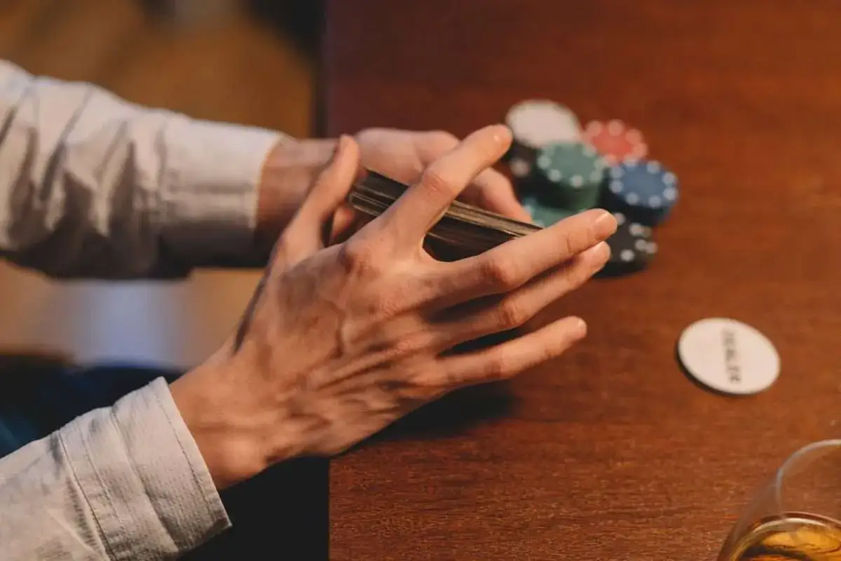 H&auml;nder som blandar kort vid ett pokerbord, med marker och en 