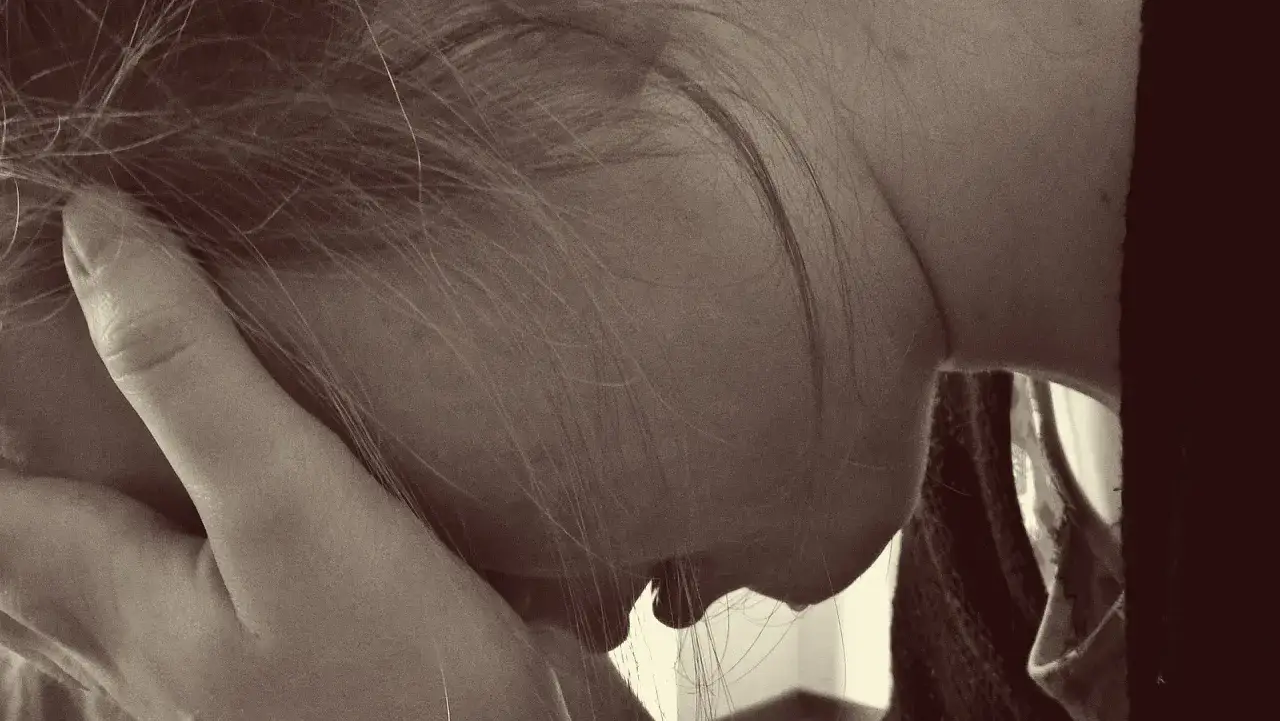 En kvinna med handen mot ansiktet, en bild som kan spegla k&auml;nslor av gravid depression och utmaningar i familjelivet.