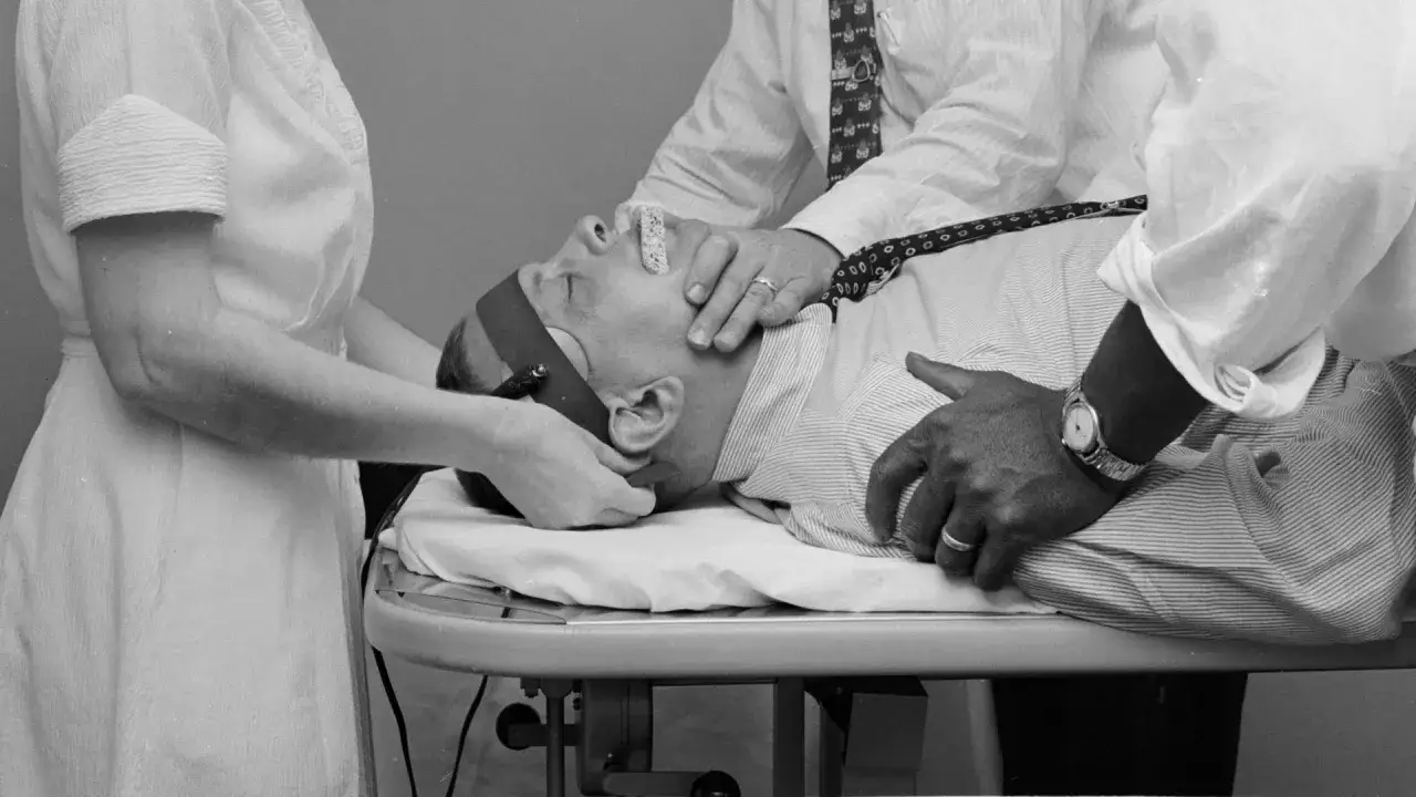Man får behandling för svår depression. Två personer håller hans huvud medan en tredje förbereder en apparat.