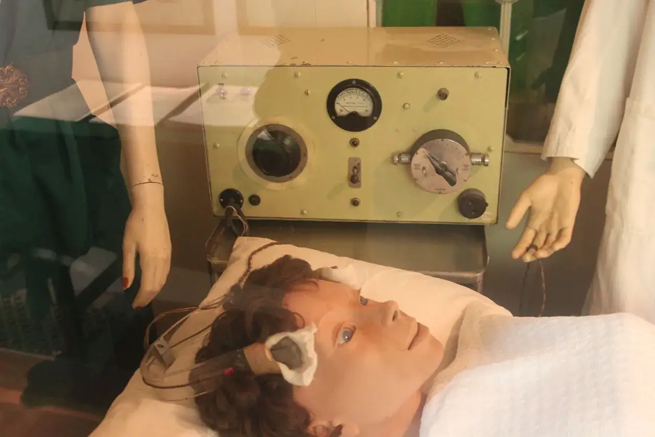 En utställning visar en historisk apparat för behandling vid depression, med en docka som patient och en docka som vårdgivare.