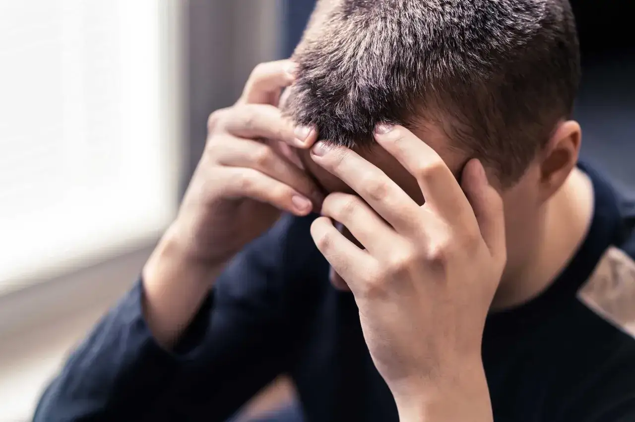 En person med händerna mot huvudet, som kämpar med akut depression.