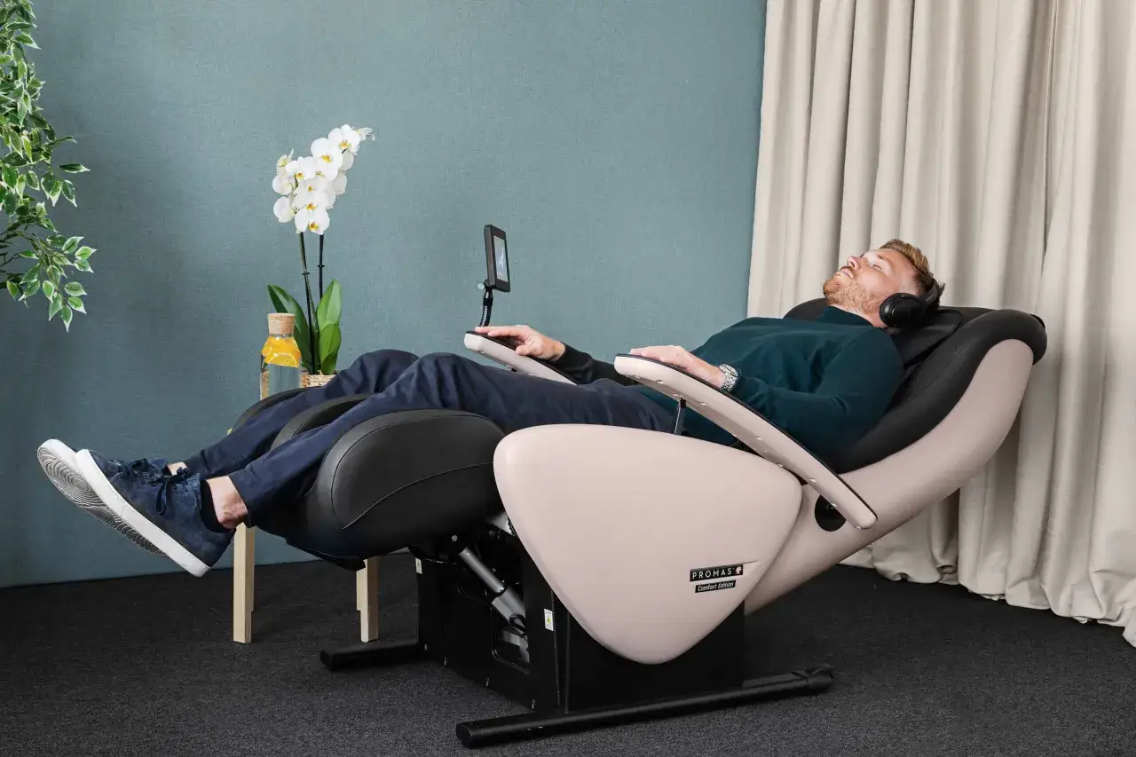 Man kopplar av i en massagestol med hörlurar, kanske för att samla kraft inför att byta jobb efter utmattning.